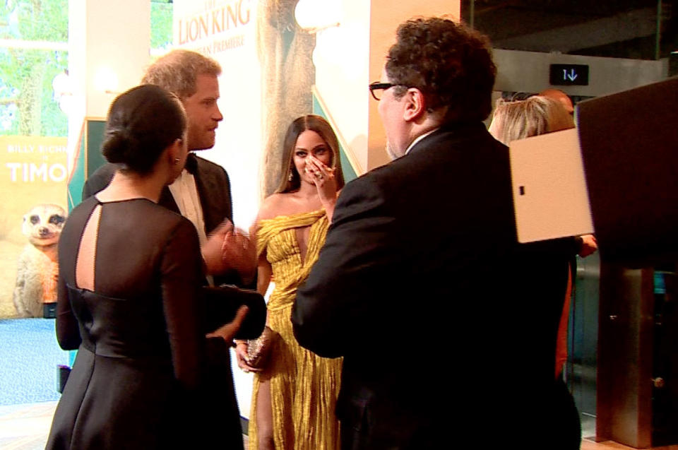 Beyonce touches her face as Prince Harry jokes about Meghan's work with Jon Favreau (left) Photo: Getty Images