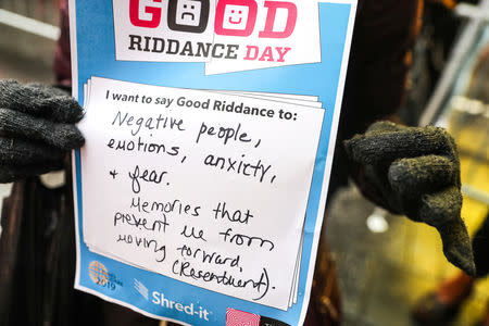 A person holds a message with a bad memory during the National Good Riddance day ceremonial shredding of bad memories of 2018 in Times Square in the Manhattan borough of New York, U.S., December 28, 2018. REUTERS/Jeenah Moon