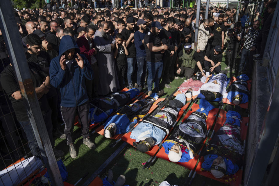 Mourners pray over the bodies of Palestinians, draped in the Islamic Jihad militant group flags, during their funeral in the Nur Shams refugee camp, near the West Bank town of Tulkarem, Sunday, April 21, 2024. The Palestinian Red Crescent rescue service said 14 bodies have been recovered from the Nur Shams urban refugee camp since an Israeli military operation began in the area Thursday night. The Islamic Jihad militant group confirmed the deaths of three members. Another killed was a 15-year-old boy. The Israeli army said its forces killed 10 militants in the camp and surrounding areas while eight suspects were arrested. (AP Photo/Nasser Nasser)