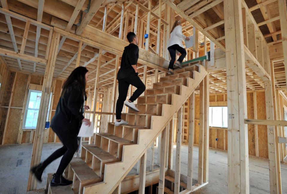 Real estate agent Alison Sheerin, right, leads Kate Isenburg, left, and her husband, Chris Isenburg, center, up the stairs to the second floor of a home under construction in the Curtis Estates in Scituate during an open house Saturday, Feb. 12, 2022.