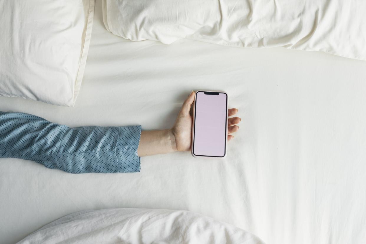 Anonymous woman's hand with a mobile phone in it (blank screen, copy space).