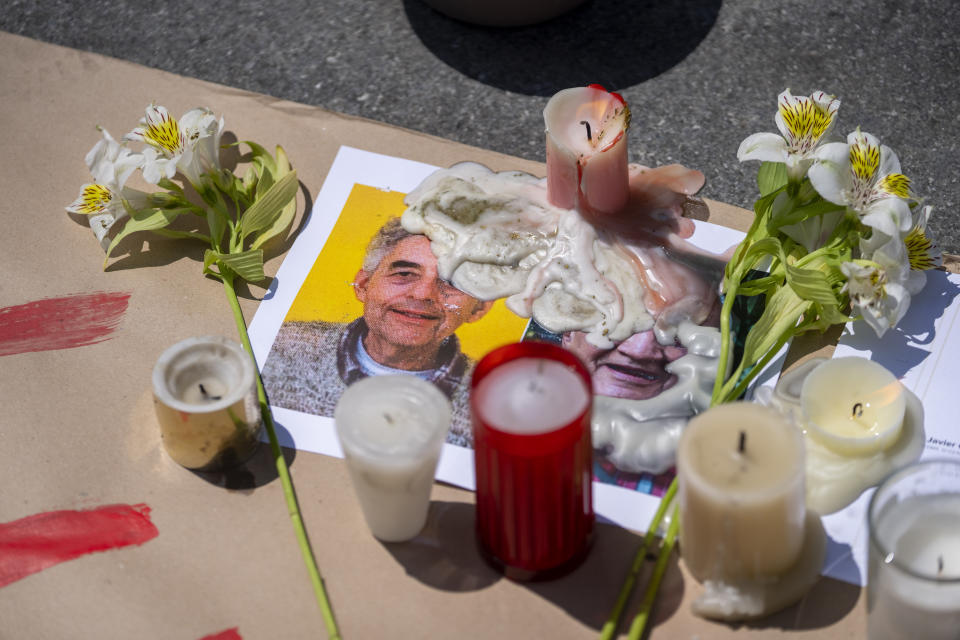 A photo of Jesuit priest Joaquin Cesar Mora Salazar is covered in candle wax on a memorial for of all priests and religious men and women who have been murdered in Mexico, in Mexico City, Sunday, July 10, 2022. In the wake of the murders of two Jesuit priests two weeks ago in Chihuahua, the Society of Jesus and other religious institutions called for a day of prayer and peace. (AP Photo/Moises Castillo)