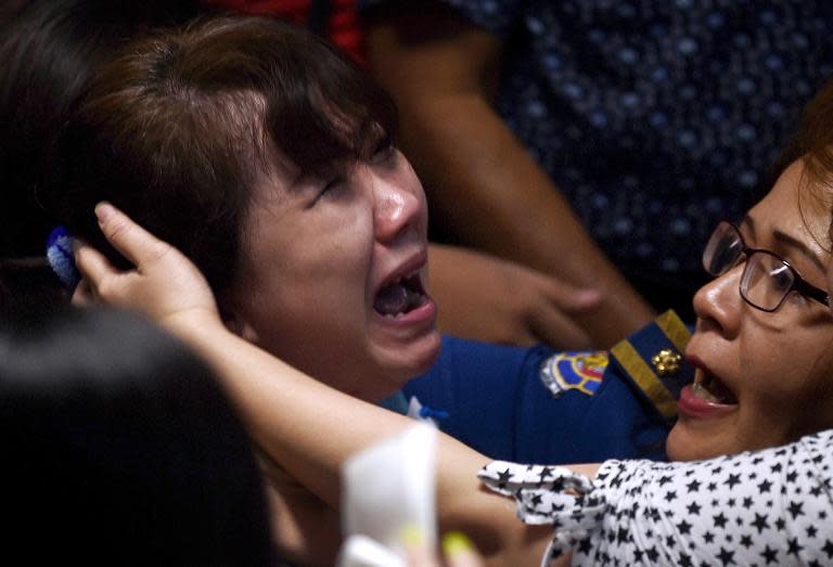 Family members of passengers onboard AirAsia flight QZ8501 react after watching television reports showing an body floating in the Java Sea, while waiting at a crisis-centre set up at Juanda International Airport in Surabaya, on December 30, 2014