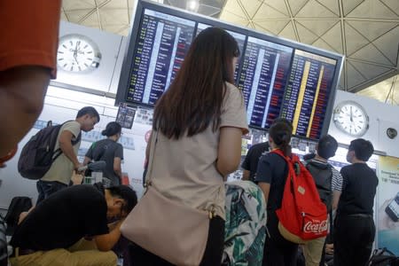 Passengers look at the departure board after all flights leaving Hong Kong were cancelled due to a protest inside the airport terminal in Hong Kong