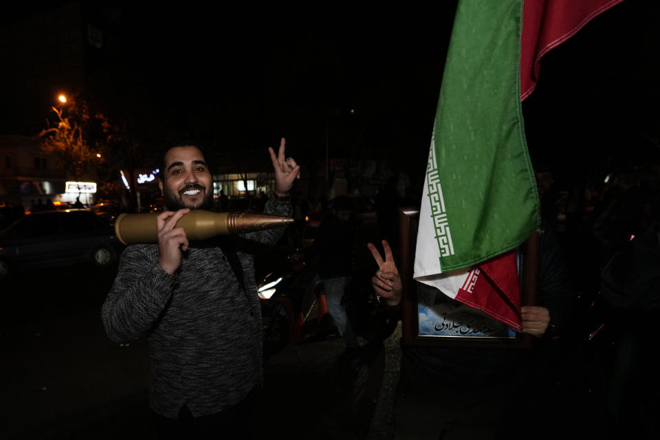 Iranian demonstrators flash the victory sign as they hold an Iranian flag and a model of a bullet during an anti-Israeli gathering at the Felestin (Palestine) Square in Tehran, Iran, early Sunday, April 14, 2024. Iran launched its first direct military attack against Israel on Saturday. (AP Photo/Vahid Salemi)