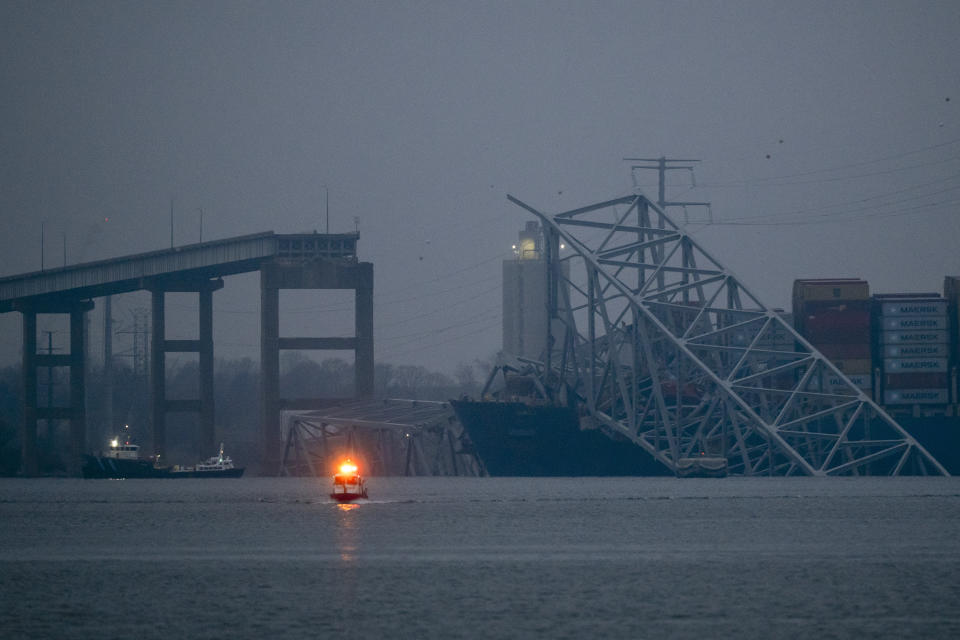 A container ship rests against wreckage of the Francis Scott Key Bridge as dawn approaches on Wednesday, March 27, 2024, in Baltimore, Md. Recovery efforts resumed Wednesday for the construction workers who are presumed dead after the cargo ship hit a pillar of the bridge, causing the structure to collapse. (AP Photo/Matt Rourke)