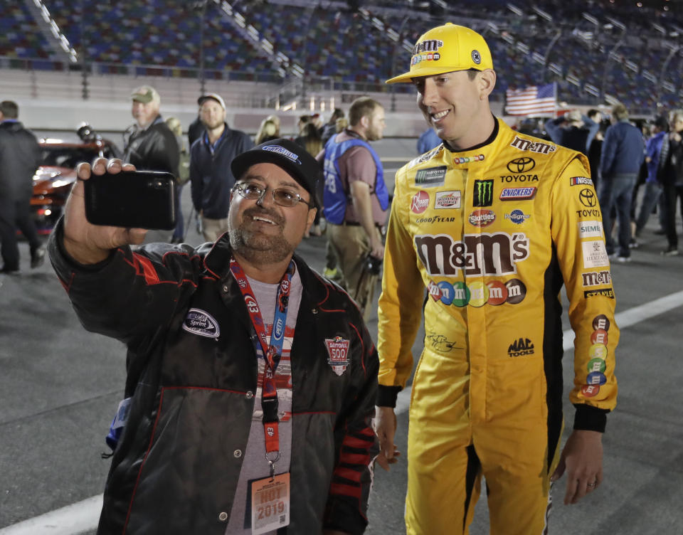 Kyle Busch, right, poses for a selfie photo with a race fan before the first of two qualifying auto races for the NASCAR Daytona 500 at Daytona International Speedway, Thursday, Feb. 14, 2019, in Daytona Beach, Fla. (AP Photo/John Raoux)