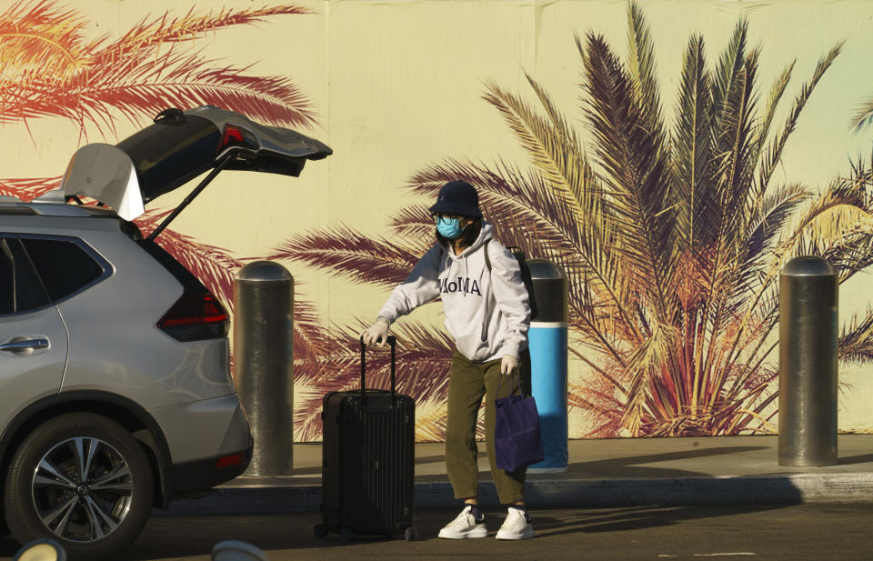 FILE - In this Nov. 13, 2020, file photo, a traveler wears a face mask and gloves at Los Angeles International Airport in Los Angeles. California has become the second state to record 1 million confirmed coronavirus infections. With the coronavirus surging out of control, the nation’s top public health agency advised Americans on Thursday, Nov. 19, not to travel for Thanksgiving and not to spend the holiday with people from outside their household. (AP Photo/Damian Dovarganes, File)