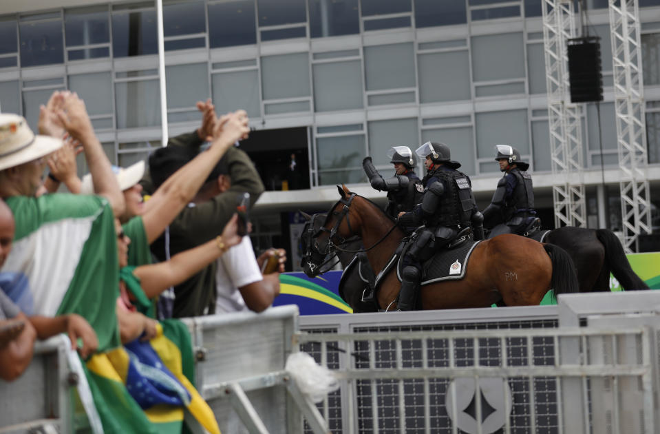People greet military police officers before the swearing-in ceremony of former army captain Jair Bolsonaro as Brazil's new President in front of the Planalto palace in Brasilia, Brail, Tuesday Jan. 1, 2019. Once an outsider mocked by fellow lawmakers for his far-right positions, constant use of expletives and even casual dressing, Bolsonaro is taking office as Brazil's president Tuesday. (AP Photo/Silvia Izquierdo)