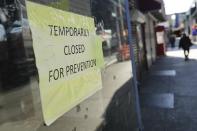 Pedestrians pass closed stores on Roosevelt Avenue Saturday, April 4, 2020, in the Queens borough of New York. The new coronavirus causes mild or moderate symptoms for most people, but for some, especially older adults and people with existing health problems, it can cause more severe illness or death. (AP Photo/Frank Franklin II)