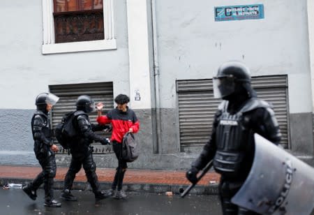 Riot police urge a man to move during a protest after Ecuadorian President Lenin Moreno's government ended four-decade-old fuel subsidies, in Quito