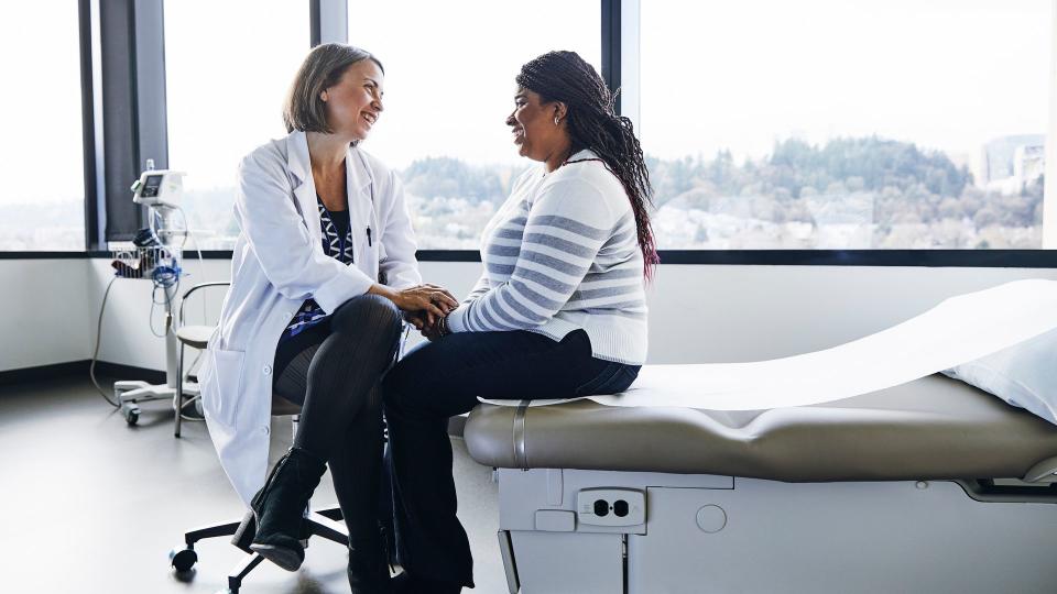 Smiling female doctor talking to woman in hospital