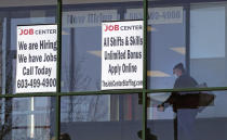 FILE - In this March 2, 2021, file photo, a woman, wearing a protective mask due to the coronavirus, walks past the signs of an employment agency, in Manchester, N.H. A new report finds that Latinas have left the workforce at rates higher than any other demographic and also have had some of the highest unemployment rates throughout the pandemic. (AP Photo/Charles Krupa, File)