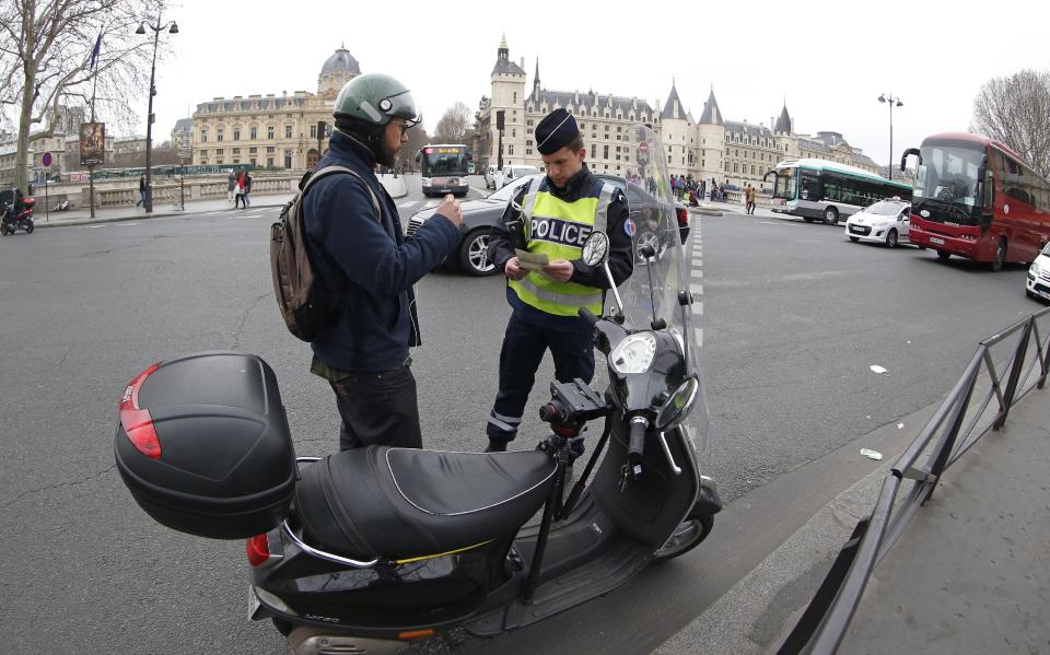 A police officer stops a scooter along the Seine river in Paris, Monday, March 17, 2014. Cars with even-numbered license plates are prohibited from driving in Paris and its suburbs Monday, following a government decision over the weekend. Paris is taking drastic measures to combat its worst air pollution in years, banning around half of the city's cars and trucks from its streets in an attempt to reduce the toxic smog that's shrouded the City of Light for more than a week. (AP Photo/Michel Euler)