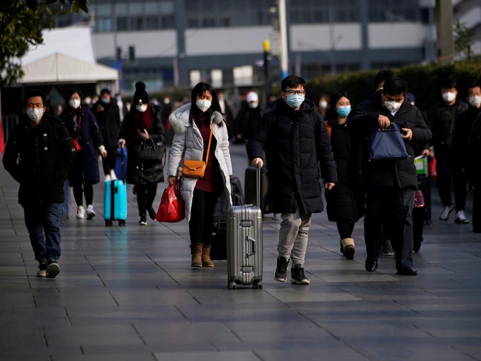 FILE PHOTO: Passengers wearing masks walk at the Shanghai railway station in China, as the country is hit by an outbreak of the novel coronavirus, February 9, 2020. REUTERS/Aly Song