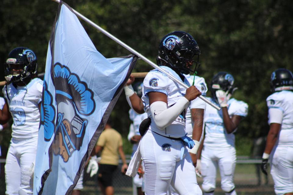 Ribault linebacker Jalen Armstead (44) carries the Trojans' flag before the Northwest Classic high school football game at Raines on October 8, 2022. [Clayton Freeman/Florida Times-Union]