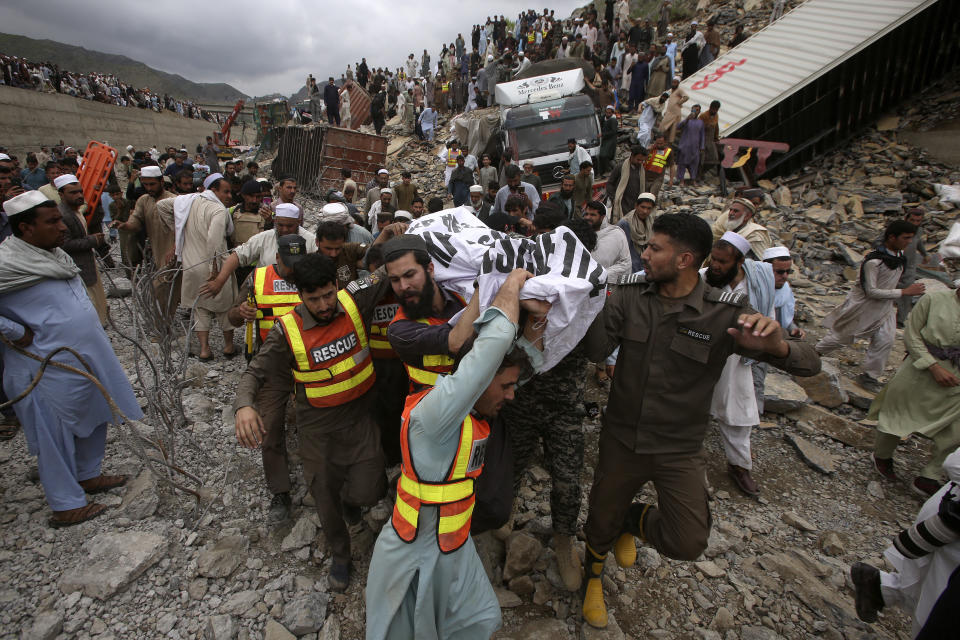 Rescue workers and volunteers carry a body after recovering it from the rubble at the site of landslide near the Torkham border town, Pakistan, Tuesday, April 18, 2023. A massive landslide struck a key highway in northwestern Pakistan near the border town of Torkham before dawn Tuesday, burying two dozen trucks, officials said. (AP Photo/Muhammad Sajjad)