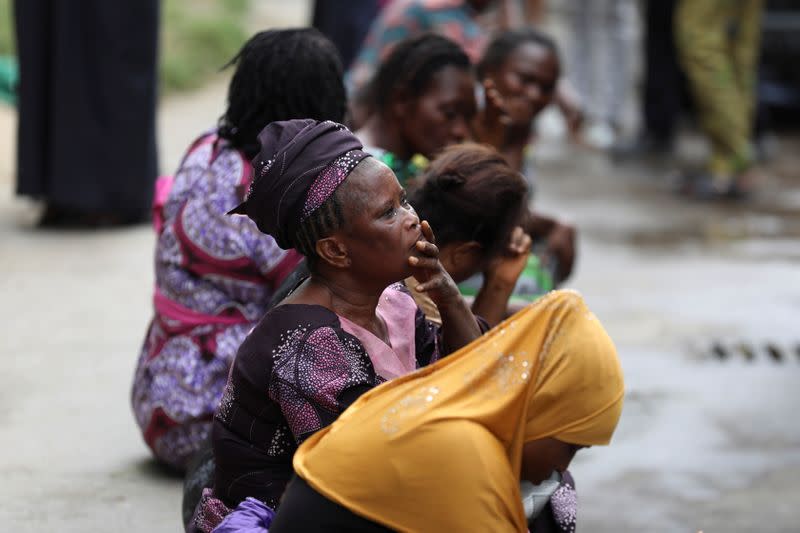 Relatives wait outside as rescue workers continue to conduct search and rescue effort at the site of a collapsed building in Ikoyi