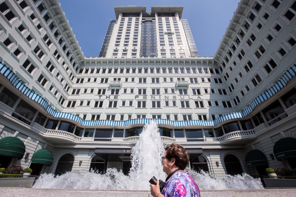 This picture taken on October 26, 2017 shows a tourist walking past the Peninsula Hotel in the Tsim Sha Tsui district of Hong Kong.  / AFP PHOTO / Isaac LAWRENCE        (Photo credit should read ISAAC LAWRENCE/AFP via Getty Images)