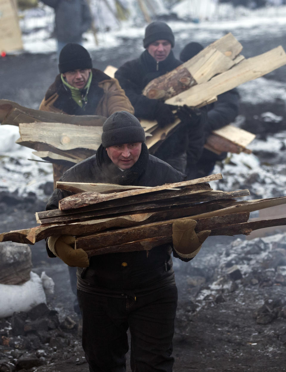 Anti-government activists carry firewood at the barricade in central Kiev, Ukraine, Friday, Jan. 31, 2014. Negotiations between the authorities and the opposition on finding a way out of the crisis appeared to have stalled on Thursday, after Yanukovych took an unexpected sick leave and told opposition leaders that it was now up to them to make concessions. (AP Photo/Darko Bandic)