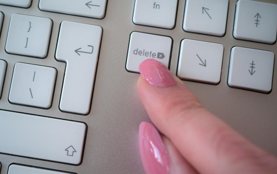Finger pressing the delete key on a keyboard