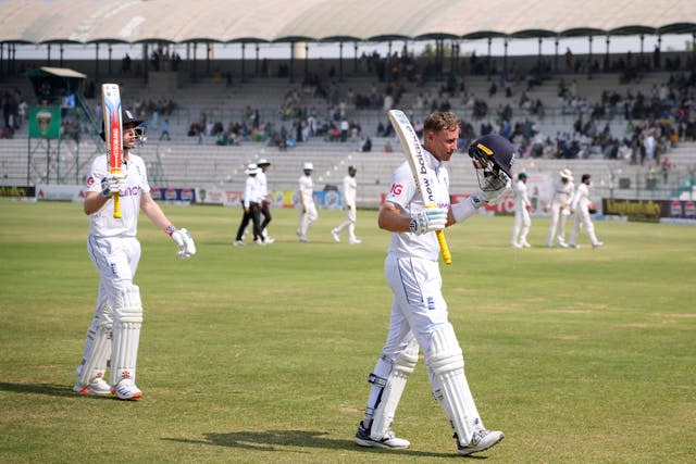 England’s Joe Root, right, and Harry Brook raise their bats to the crowd as they leave the field at lunch in Multan