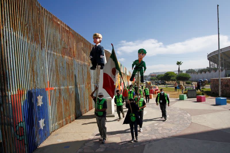 Migrants and members of civil society hold pinatas during a protest in Tijuana