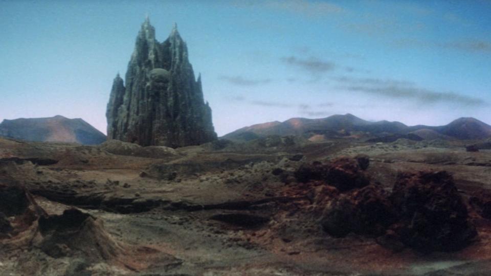 Still from the science fantasy movie Krull (1983). A giant black fortress (an interplanetary spaceship/castle) lands on the desert-like terrain of the planet Krull.