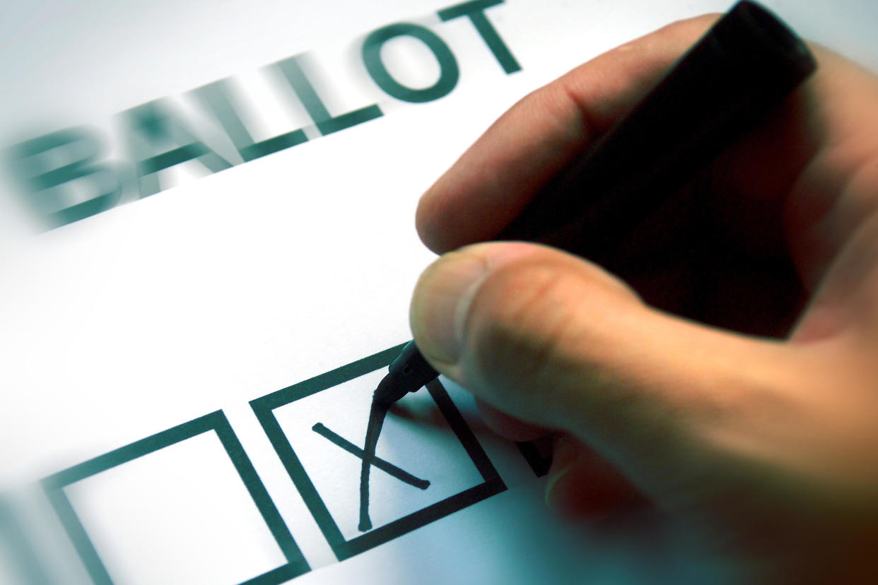 A hand writing a cross on a ballot paper