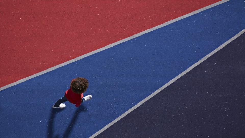 Un niño camina sobre una línea azul