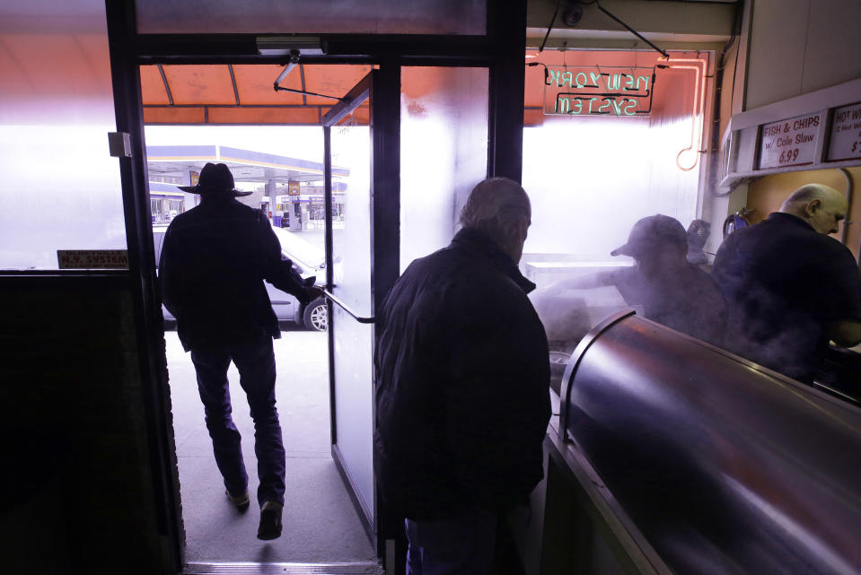 In this Monday, March 3, 2014 photo a customer leaves with his order to-go as another places his at Olneyville New York System of Providence in Providence, R.I. The James Beard Foundation named the Rhode Island restaurant one of five "American Classics". (AP Photo/Stephan Savoia)