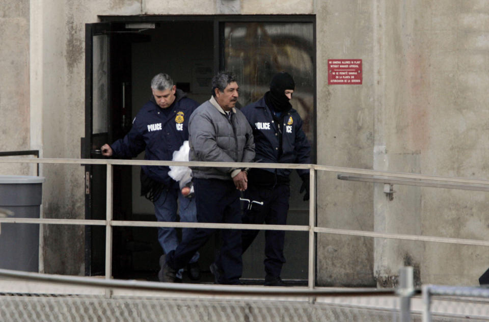 An unidentified Swift & Co. employee is escorted out of the Greeley Lamb Plant 