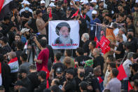 FILE - Supporters of Iran-backed Shiite Coordination Framework attend a rally to denounce their rivals, followers of an influential Shiite cleric Muqtada al-Sadr who stormed the parliament last month and have since been holding a sit-in outside the assembly building in Baghdad, Iraq, Friday, Aug. 12, 2022. On the photo is a revered Shiite Grand Ayatollah Ali al-Sistani. (AP Photo/Anmar Khalil, File)