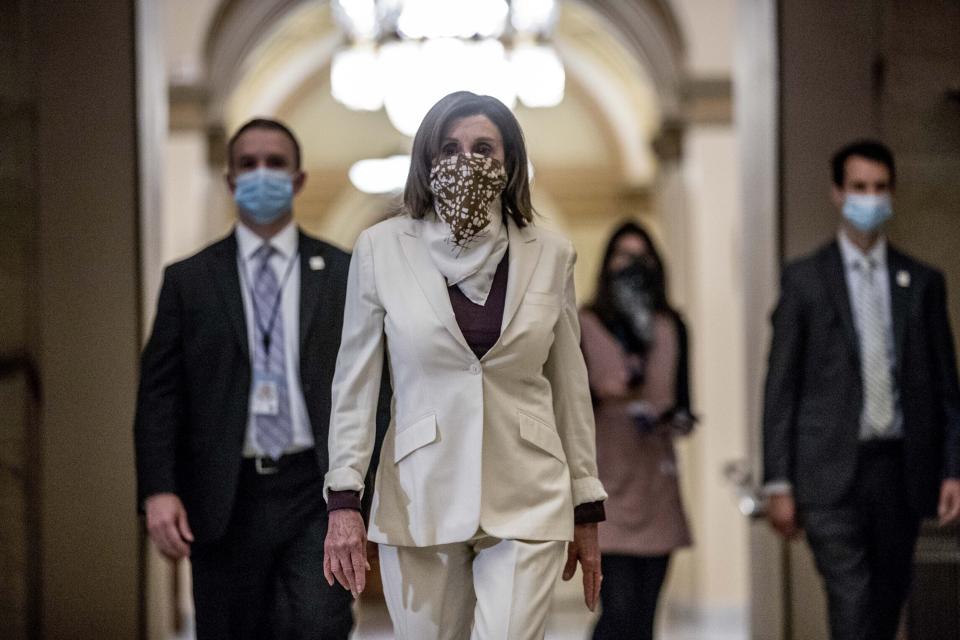 FILE - In this Thursday, April 23, 2020 file photo, House Speaker Nancy Pelosi, D-Calif., walks to her office after signing the Paycheck Protection Program and Health Care Enhancement Act, H.R. 266, after it passed the House on Capitol Hill in Washington. On Friday, April 24, 2020, The Associated Press reported on a social media posts circulating online incorrectly asserting “Worst pandemic in 100 years, what does Congress do? Takes a paid vacation.” Congressional leaders from both parties have been in Washington to hammer out deals in recent days. (AP Photo/Andrew Harnik)