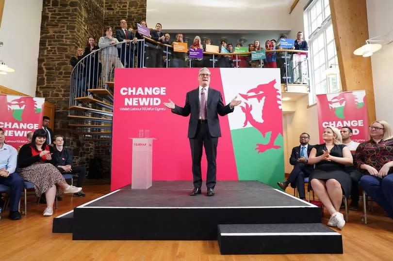 Sir Keir Starmer on a stage with a red background including a dragon at a campaign event in Wales