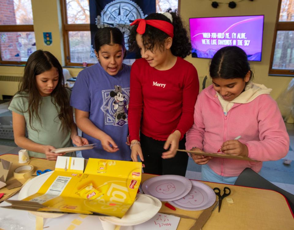 Fifth-grade students build a bridge during an after-school program Thursday at Girls Inc. The STEM challenge involved making a bridge from common objects and testing its strength by adding pennies for weight.