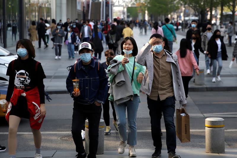 People wearing face masks are seen at a shopping area in Beijing