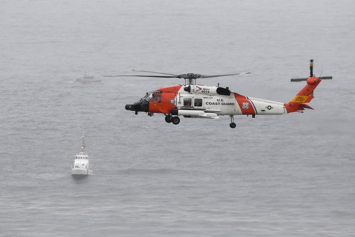 A U.S. Coast Guard helicopter flies over boats searching the area where a boat capsized just off the San Diego coast Sunday, May 2. 