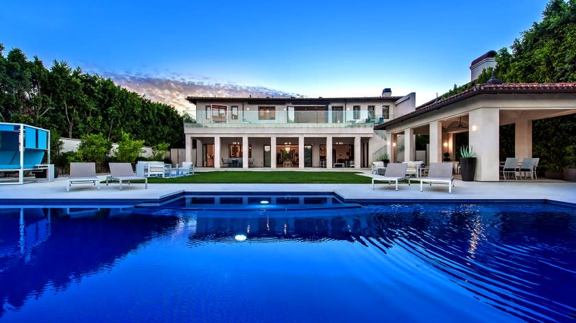 A gated driveway approaches the 13,300-square-foot home lined with oval windows and wrought-iron accents. The eight-bedroom, 12-bathroom home opens to a 25,000-gallon pool surrounded by a pavilion, lounge and lawn. (Marc Angeles / Unlimited Style Real Estate Photography)