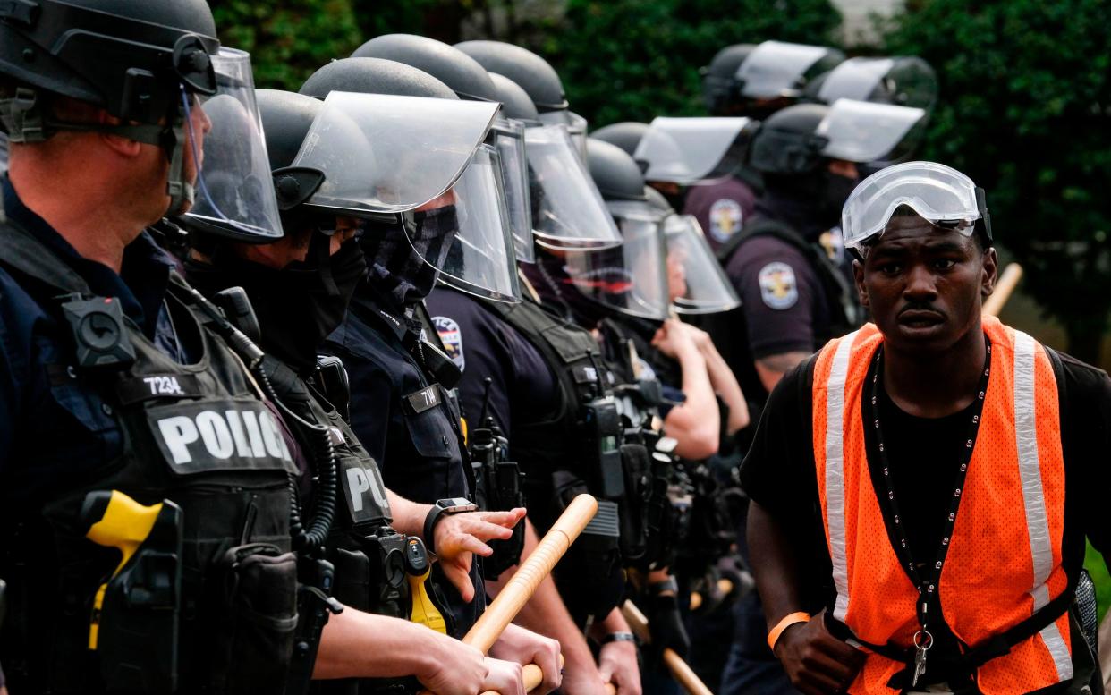 A protestor marches by a police line in downtown Louisville, Kentucky, -  JEFF DEAN/ AFP