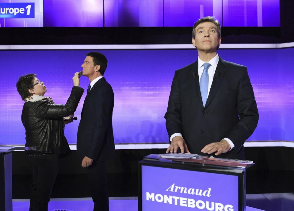 Former Prime minister Manuel Valls, left, receives make up while former Economy minister Arnaud Montebourg looks on, before taking part in a final televised debate of the candidates for the French left's presidential primaries ahead of the 2017 presidential election in Paris, France, Thursday, Jan. 19, 2017. Seven competitors are bidding to be the Socialist Party's candidate in next spring's French presidential election. (Eric Feferberg/Pool Photo via AP)