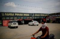 A man rides a motorcycle past a dhaba, a small restaurant along a national highway in Gharaunda