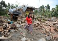 A woman walks amongst debris next to her damaged house in the village of Andap. The death toll from a typhoon that ravaged the Philippines jumped to 274 Wednesday with hundreds more missing, as rescuers battled to reach areas cut off by floods and mudslides