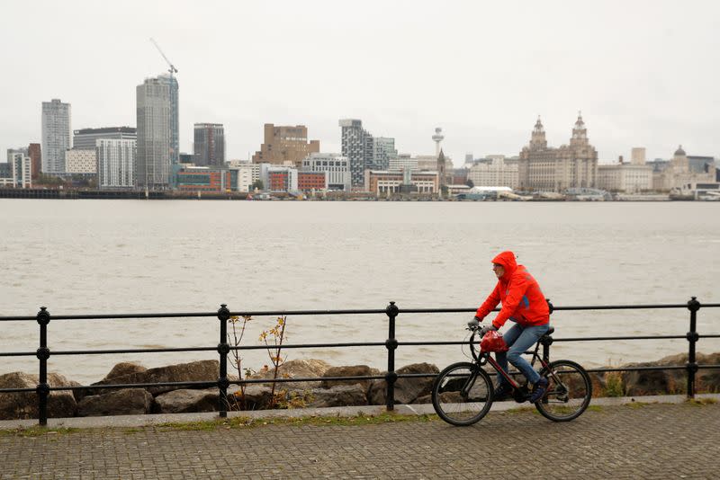 A man cycles along the River Mersey with the Liverpool skyline in Seacombe