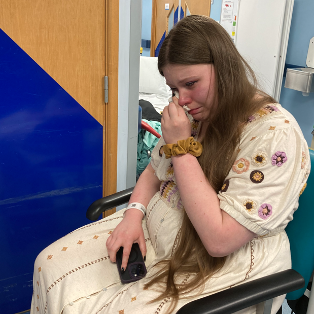 Johanna sitting in a hospital padded chair crying