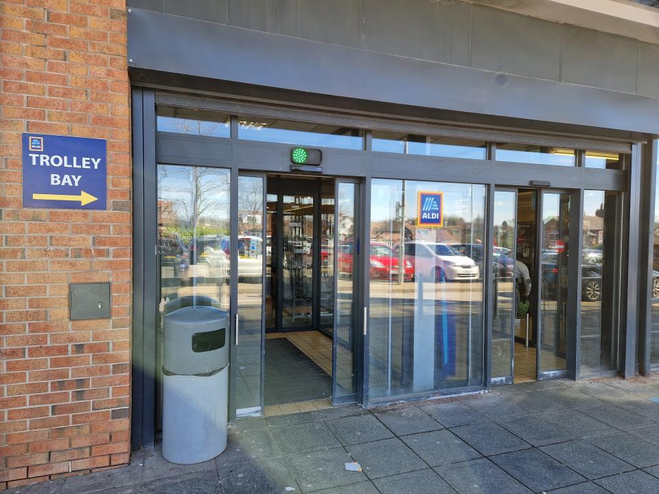 Sliding door entrance area of UK Aldi with a "trolley bay" sign on building