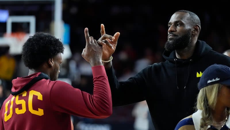 Southern California guard Bronny James, left, high-fives his father, Los Angeles Lakers' LeBron James, as he warms up before a game against Stanford in Los Angeles, Saturday, Jan. 6, 2024.