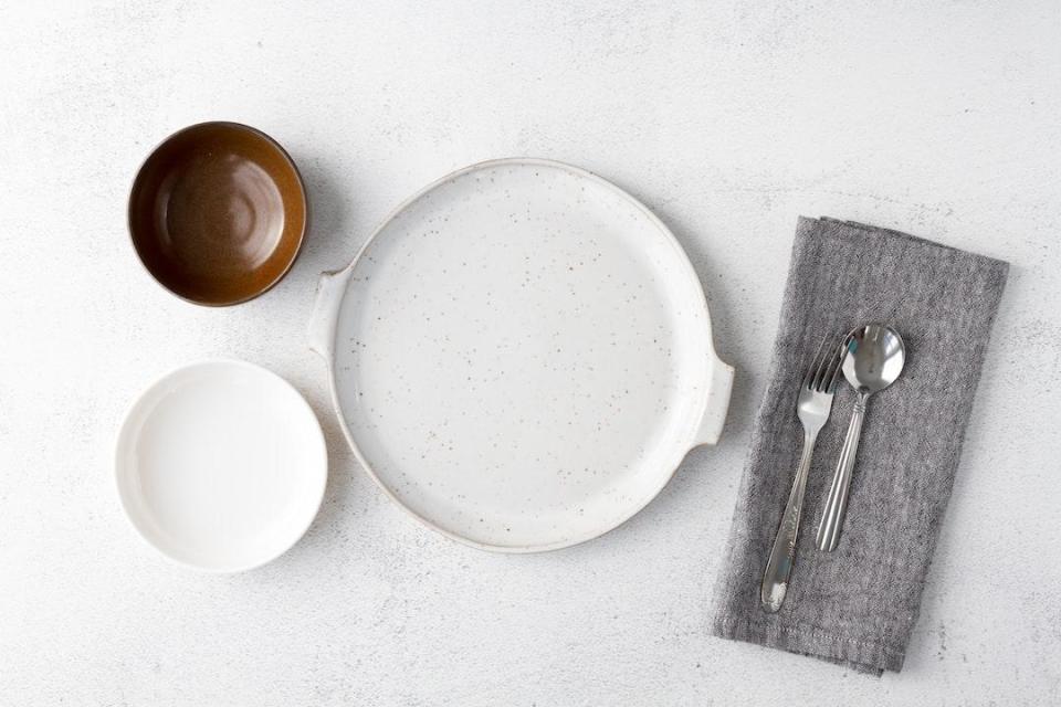 A place setting with silverware and a napkin on a white table