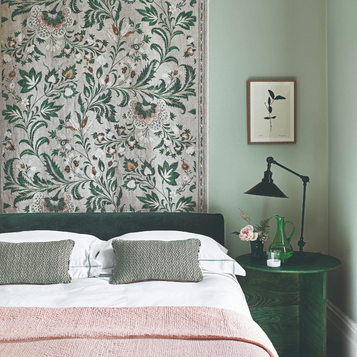  A green-painted bedroom with a floral wall tapestry. 