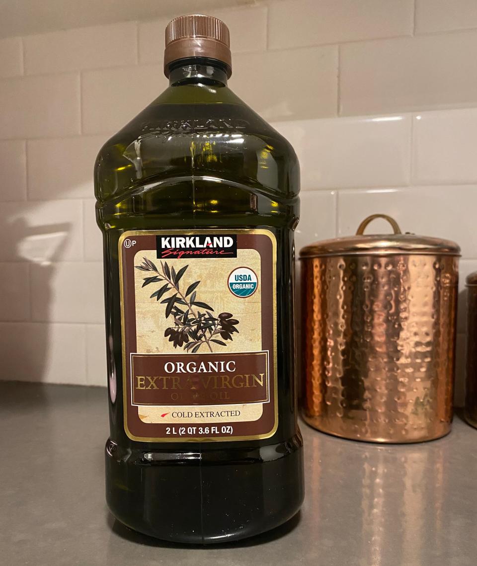 Large, green-ish bottle of olive oil from Costco on kitchen counter